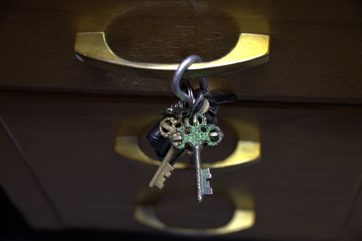 Antique keys attached to the handle of a desk drawer. 