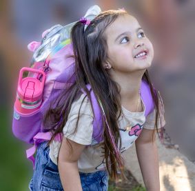 Young girl with a backpack smiling and ready to go
